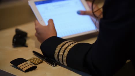 Unrecognizable-female-pilot-preparing-flight-documentation-on-a-tablet
