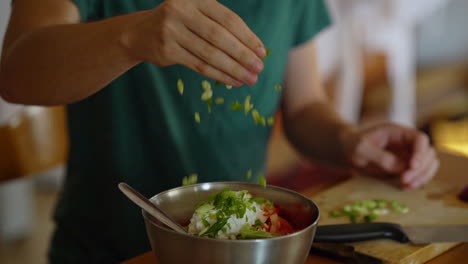 man-adds-chopped-green-onion-to-a-salad,-filmed-in-slow-motion