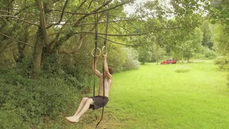 Athletic-young-man-doing-ring-pullups-in-garden