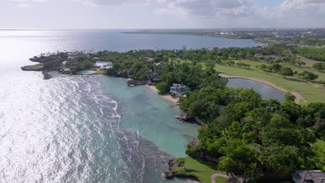 Aerial-flyover-Casa-de-Campo-La-Romana-WITH-lake,-private-pool-and-sandy-beach-in-summer---Punta-Aguila,-Dominican-Republic