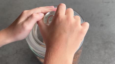 Kid-hands-struggle-to-open-the-lid-from-cookie-jar-so-takes-away-full-container