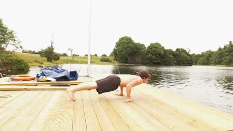 Young-man-does-planche-pushups-on-jetty-by-river