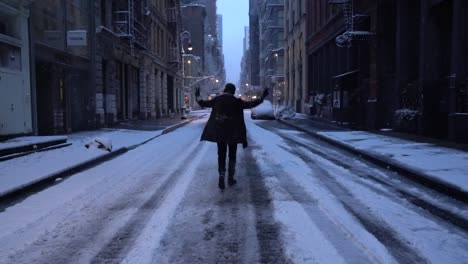 Man-walks-away-moodily-away-from-the-camera-making-victory-sign-on-snowy-street-in-Soho,-Manhattan