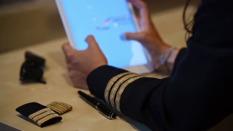 Unrecognizable-female-pilot-preparing-flight-documentation-on-a-tablet