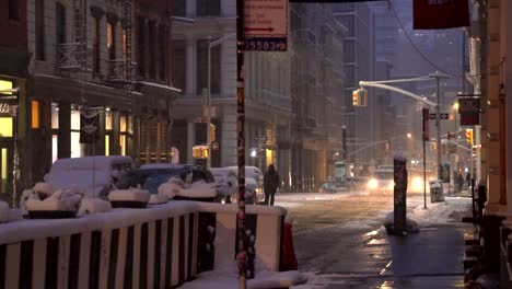Cars-with-headlights-on-during-snowy-morning-before-sunrise-in-Soho,-Manhattan,-New-York