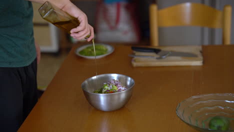 Man-adds-olive-oil-to-a-salad,-filmed-in-slow-motion