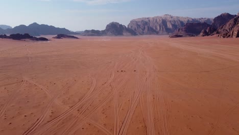 Aerial-view-of-a-camel-family-walking-through-the-Wadi-Rum-Desert-in-Jordan