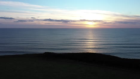 Eine-Langsame-Luftaufnahme-Eines-Sonnenuntergangs-über-Den-Klippen-Von-South-Devon-In-Der-Nähe-Von-Challyborough
