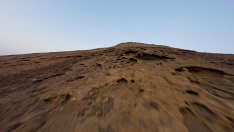 Fuerteventura-Landscape-FPV-rocky-Vulcan-Mountain-rise-with-view-over-east-coast-city-slowmotion