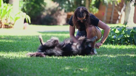 A-young-caucasian-woman-plays-with-her-black-dog-in-the-garden-of-a-house-on-a-sunny-day