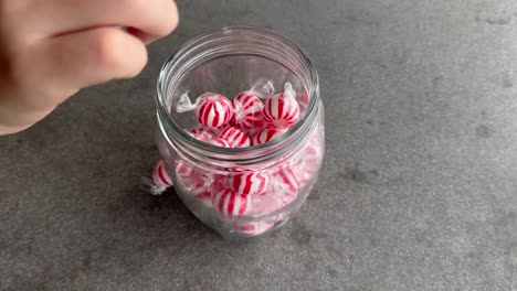 Kid-hand-takes-candy-out-of-a-glass-jar-and-then-takes-entire-jar