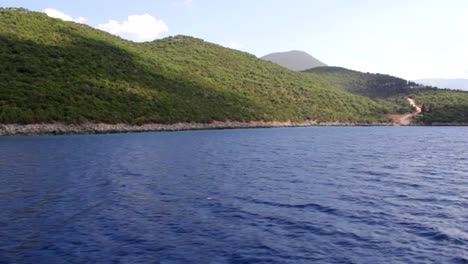 Die-Grüne-Landschaft-Der-Küste-Von-Ithaka,-Gesehen-Durch-Ein-Kreisförmiges-Fenster-Eines-Bootes