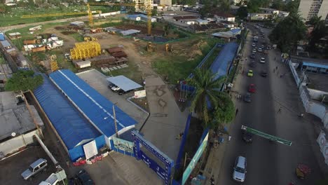 Douala-Construction-Park-Von-Oben-Gesehen,-Während-Sich-Die-Drohne-Langsam-Senkt,-Um-Mehr-Von-Den-Belebten-Straßen-Darunter-Freizulegen
