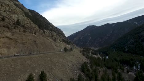 Drone-aerial-flying-to-the-right-next-to-a-highway-in-a-mountain-pass