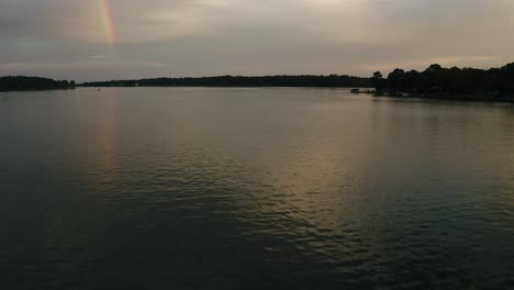 Late-Afternoon-Sunset-Rainbow-Reflecting-off-Calm-Lake-Waters-After-Summer-a-Storm-Aerial-View