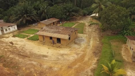 Aerial-view-of-houses-near-dirt-road,-surrounded-by-trees-in-Kribi-in-Cameroon,-west-Africa