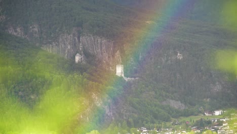 Rainbow-in-front-of-ancient-Castle-Ruin-and-a-Forest-with-a-Village-in-the-background-in-Tyrol,-Austria
