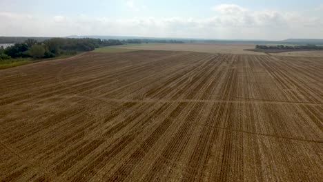 Low-flying-aerial-over-a-recently-plowed-farmland-on-a-sunny-day