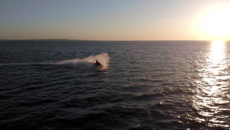A-Woman-on-a-Jet-Ski-Splashes-Through-Waves-on-an-Open-Ocean-During-Sunset