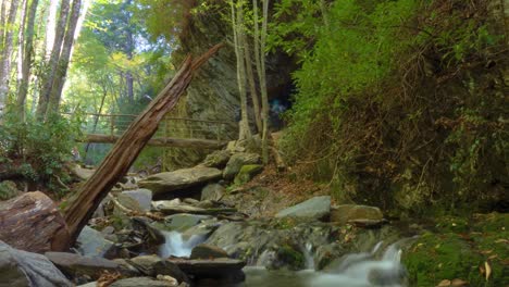 Motion-time-lapse-over-stream-with-a-bridge-over-a-waterfall-in-the-background