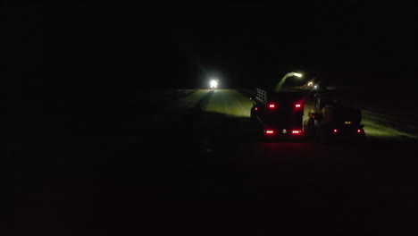 Following-aerial-footage-of-Chopper-farm-vehicles-working-by-spotlight-at-night