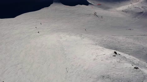 Drohnenansicht-Mit-Blick-Auf-Skifahrer,-Die-Eine-Große-Piste-In-Den-Bergen-Hinunterfahren-Und-Kleine-Und-Große-Kurven-Machen