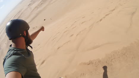 Guy-on-a-sand-board-filming-himself-travelling-down-slope