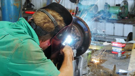 Man-welding-disc-in-garage-car-workshop