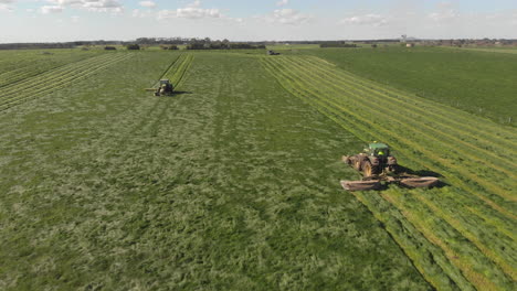 Aerial-ascending-rotation-around-two-tractor-mowers-working-the-same-paddock-field