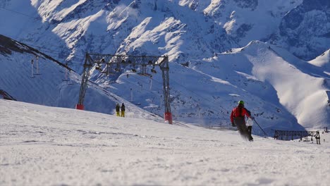 Nicht-Erkennbarer-Skifahrer,-Der-An-Einem-Sonnigen-Tag-In-Den-Bergen-Die-Piste-Hinunterfährt-Und-Schnee-Mit-Einer-Riesigen-Bergkulisse-Besprüht