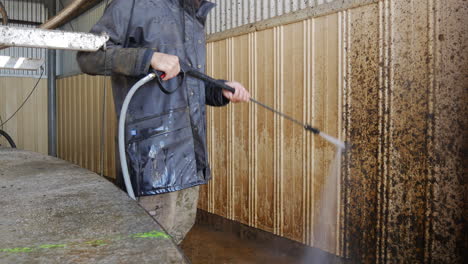 High-power-jet-washer-cleaning-grime-of-farm-barn-wall