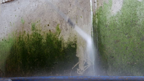 High-pressure-jet-wash-cleaning-green-substance-off-metallic-surface