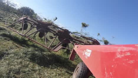 Farming-vehicle-lifting-grass-spreader---lowering-on-grassy-field