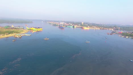 Drone-shot-flying-across-a-fishing-harbour-showing-anchored-boats-and-a-fisherman-fishing-with-a-net