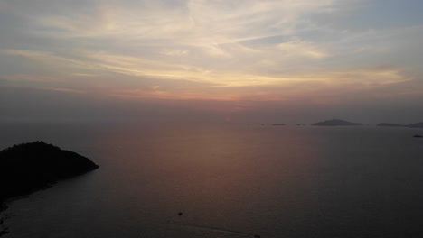 Luftaufnahme-Des-Ozeans-Bei-Einem-Sonnenuntergang-Mit-Booten-Und-Bergen-Im-Hintergrund