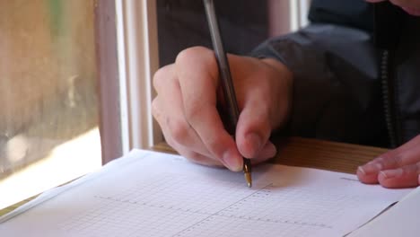 Estudiante-Escribiendo-En-Papel-Cuadriculado-De-Cerca