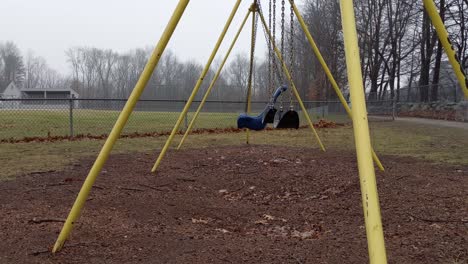 Deserted-playground-swings-through-the-frame-swinging-empty-and-lonely-on-a-rainy-and-dreary-day