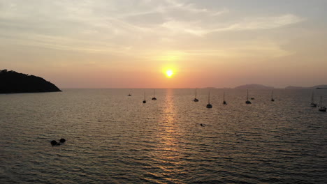 Friedlicher-Ozean-Mit-Einem-Goldenen-Sonnenuntergang,-Booten-Und-Bergen-Im-Hintergrund