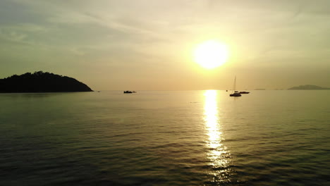 Tiefflug-über-Den-Ozean-Mit-Goldenem-Sonnenuntergang-Und-Booten-Im-Hintergrund
