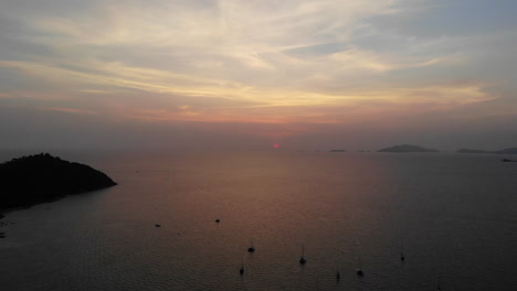 Sonnenuntergang-über-Dem-Ozean-Mit-Booten-Und-Bergen-Im-Hintergrund