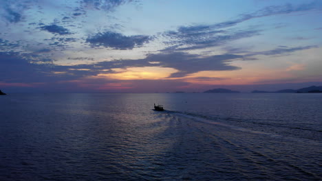 Aerial-footage-of-a-tale-boat-sailing-towards-the-sunset-in-Thailand