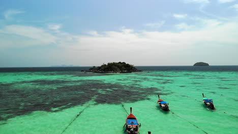 Flight-over-boats-anchored-and-clear-water-with-small-island-of-rocks-at-the-end