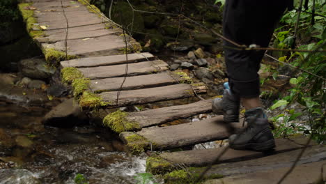 Hanging-Old-Mossy-Bridge-with-River-under-it-Tourist-Walks-Over-in-Slow-Motion