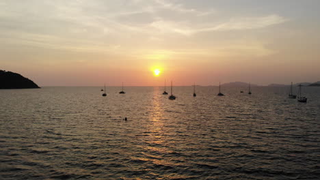 Flug-über-Das-Meer-Und-Boote-Mit-Einem-Goldenen-Sonnenuntergang-Im-Hintergrund