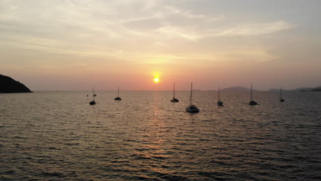 Rückwärtsflug-über-Das-Meer-Mit-Sonnenuntergang-Und-Booten-Im-Hintergrund