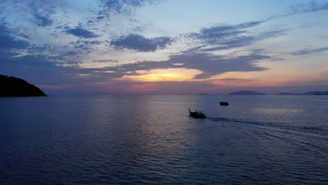 Aerial-footage-of-a-tale-boat-sailing-towards-the-sunset-among-other-boats