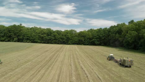 Aerial-Drone-Shot-Flying-Over-Tractors-Harvesting-in-Hay-Field