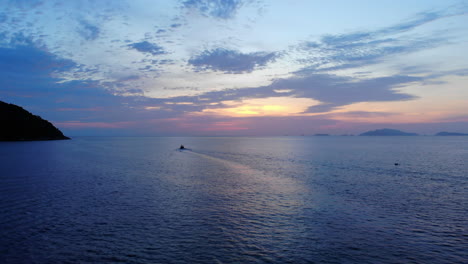 Luftaufnahme-Des-Ozeans-Mit-Einem-Boot,-Felsen-Und-Einem-Farbenfrohen-Sonnenuntergang