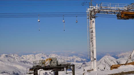 visually-pleasing-view-of-t-bar-ski-lift-passing-by-and-going-round-at-the-end-of-the-piste,-beautiful-backdrop-of-mountains-on-a-sunny-day-with-lots-of-snow
