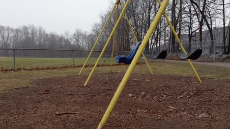 Deserted-playground-swings-swinging-empty-and-lonely-on-a-rainy-and-dreary-day